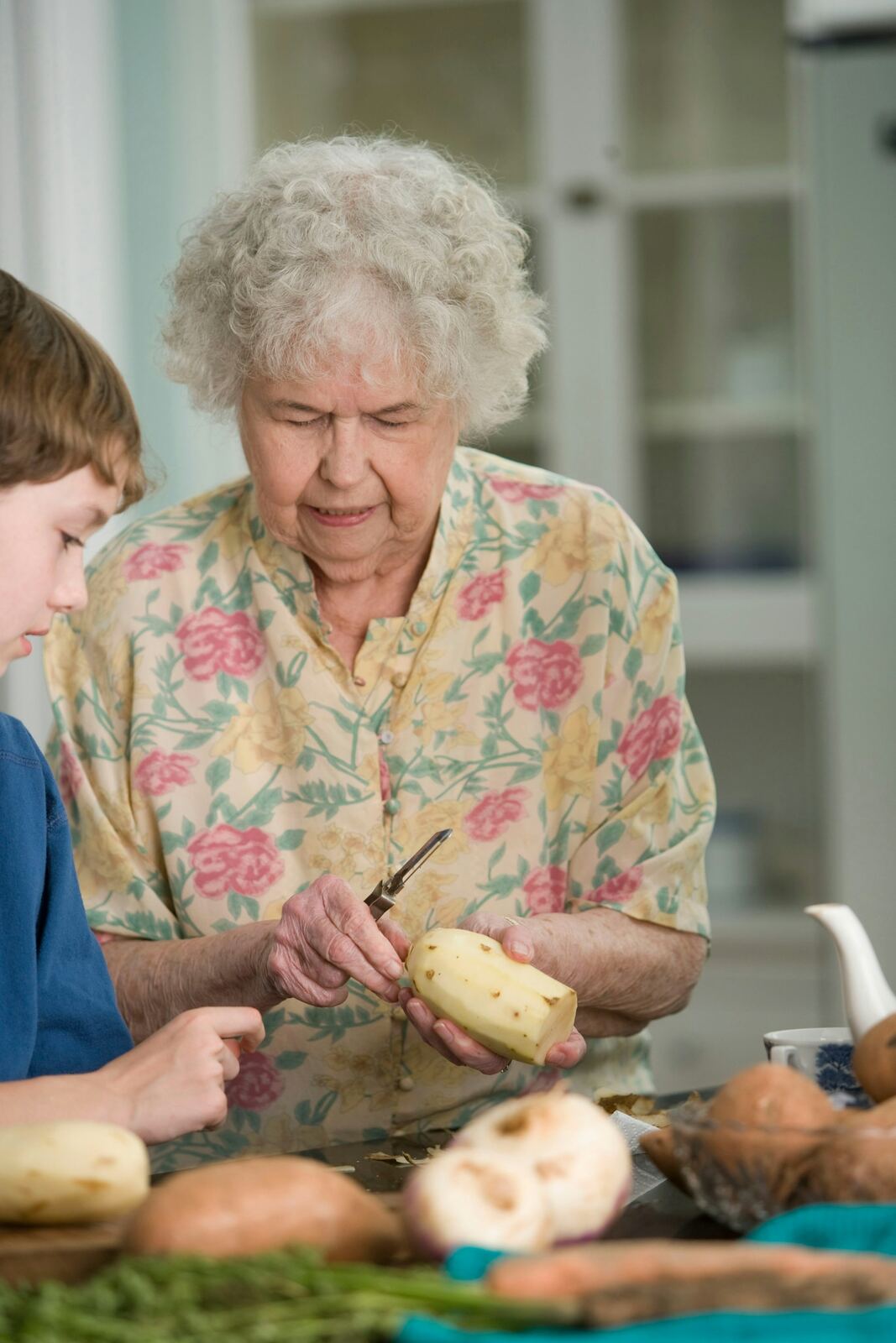 A grandparent and child preparing food together in a kitchen