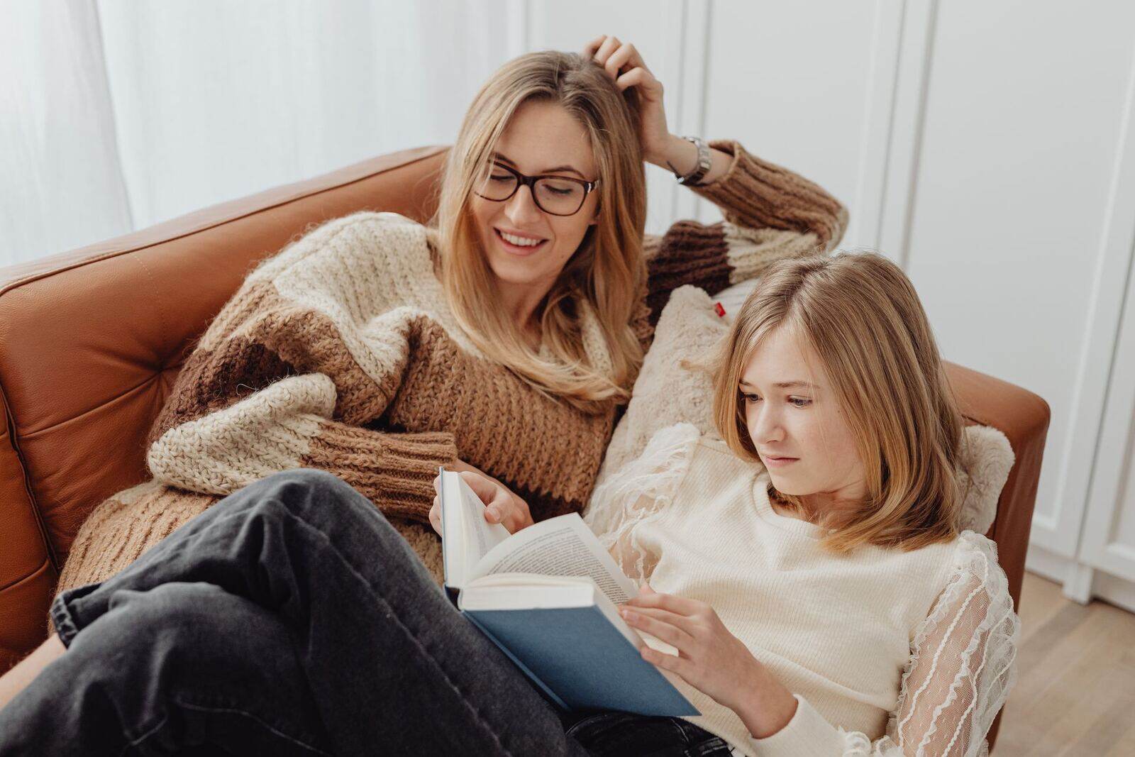 A mother and teenager relaxing together on a sofa at home
