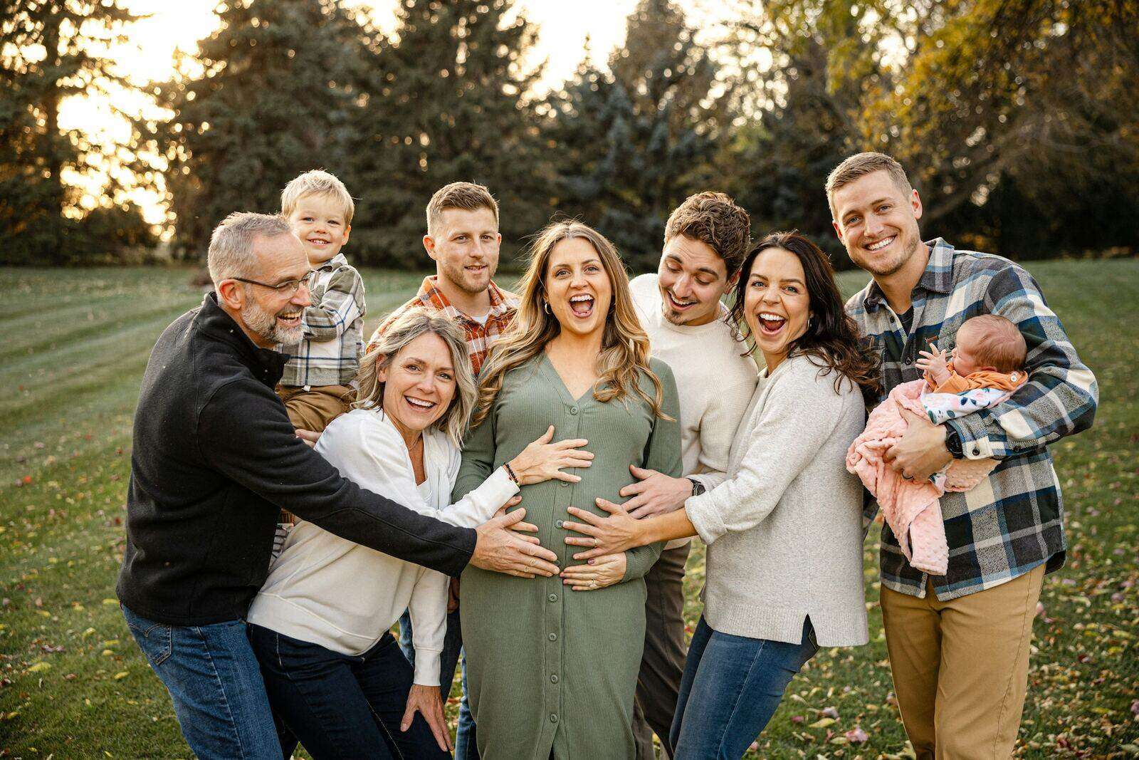 A large multi-generational family gathered together outdoors, welcoming a new baby